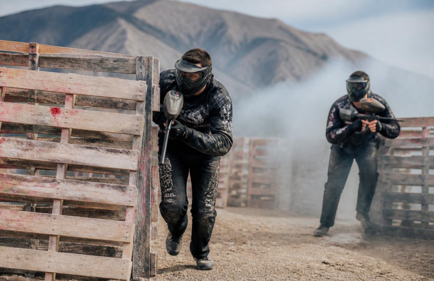 Echipă de paintball avansând tactic printre paleți
