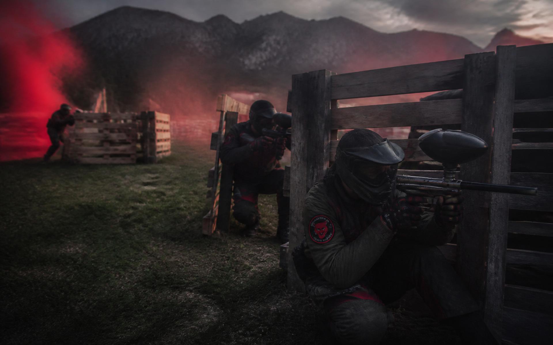 Jucători de paintball adăpostiți după obstacole din paleți pe terenul Red Alert Games